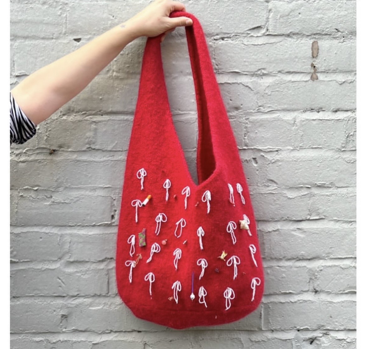 Bag made with 100% pure British sheep roving wool. Knitted oversized and felted through machine washing. Embellished with found charms and bows made of glass beads.